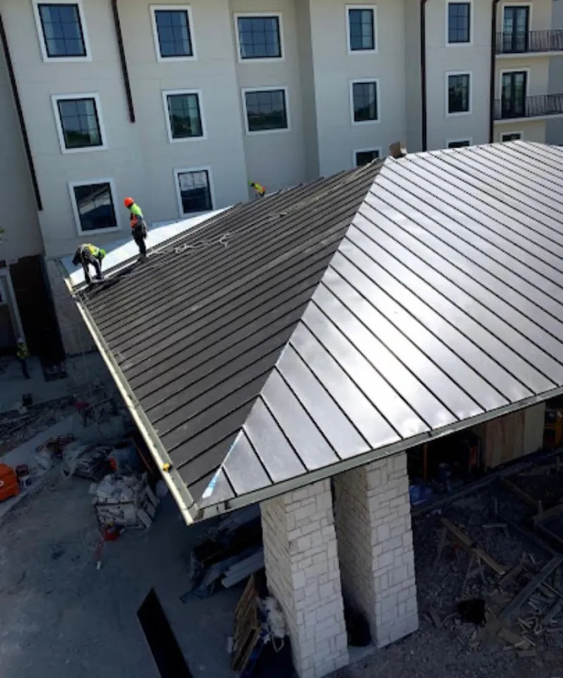 Crew installing standing seam metal roof panels on a commercial project in Lancaster